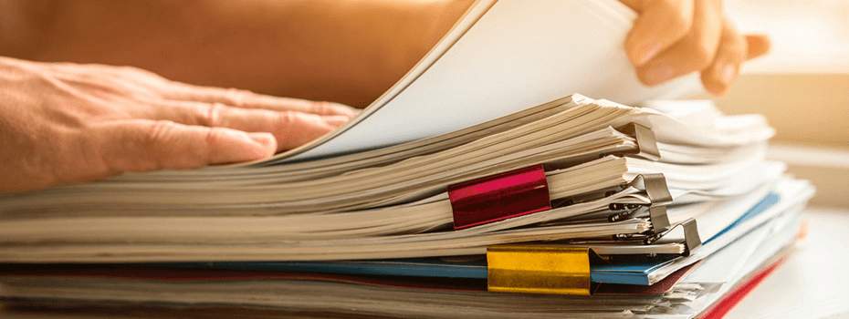 A hand picking up a collection of documents from a stack